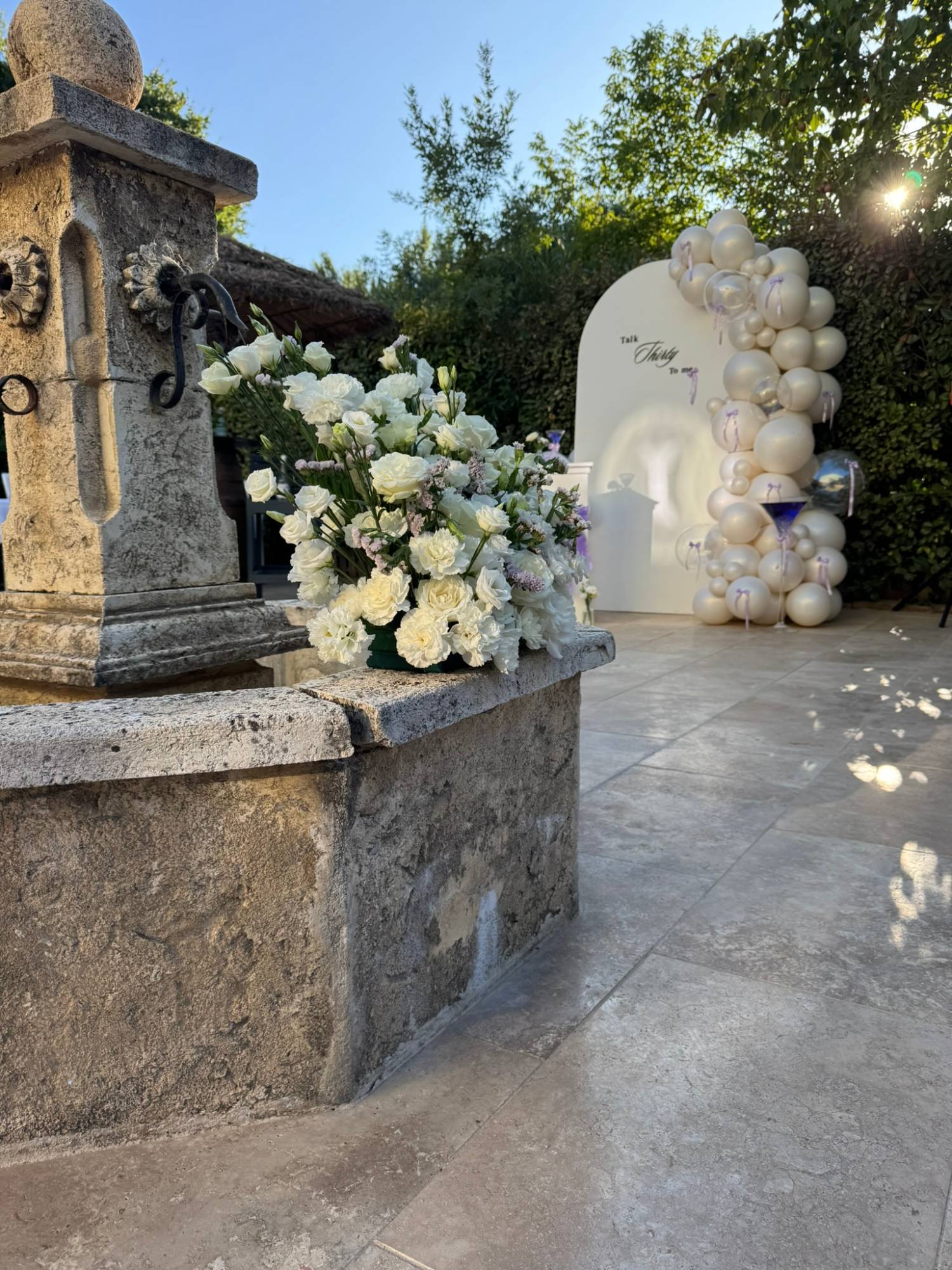Composition de fleurs blanches sur la fontaine, avec le backdrop « Talk Thirty to me » en arrière-plan