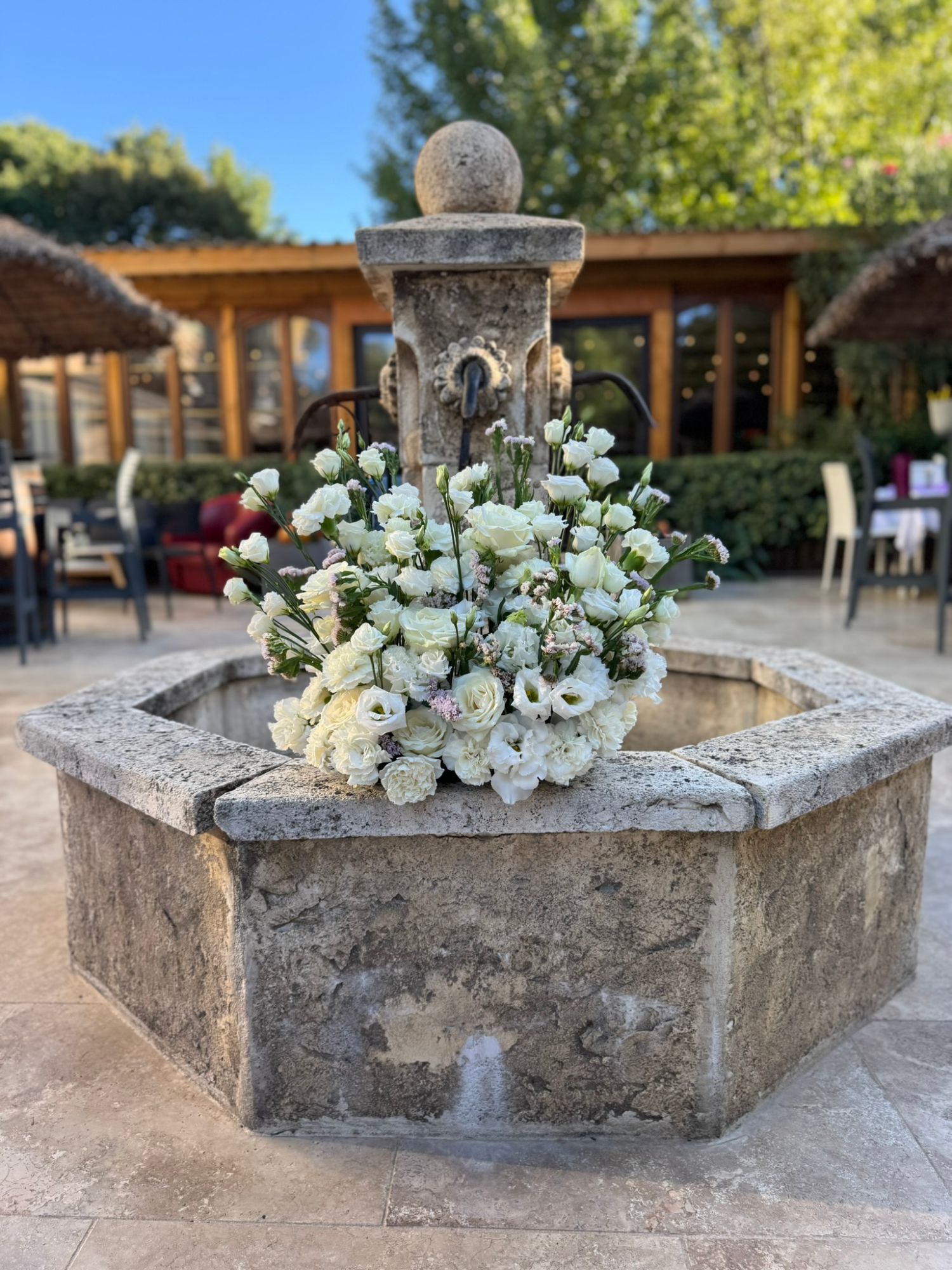 Bouquet blanc posé sur la margelle d'une fontaine en pierre, décoration d'anniversaire en Provence