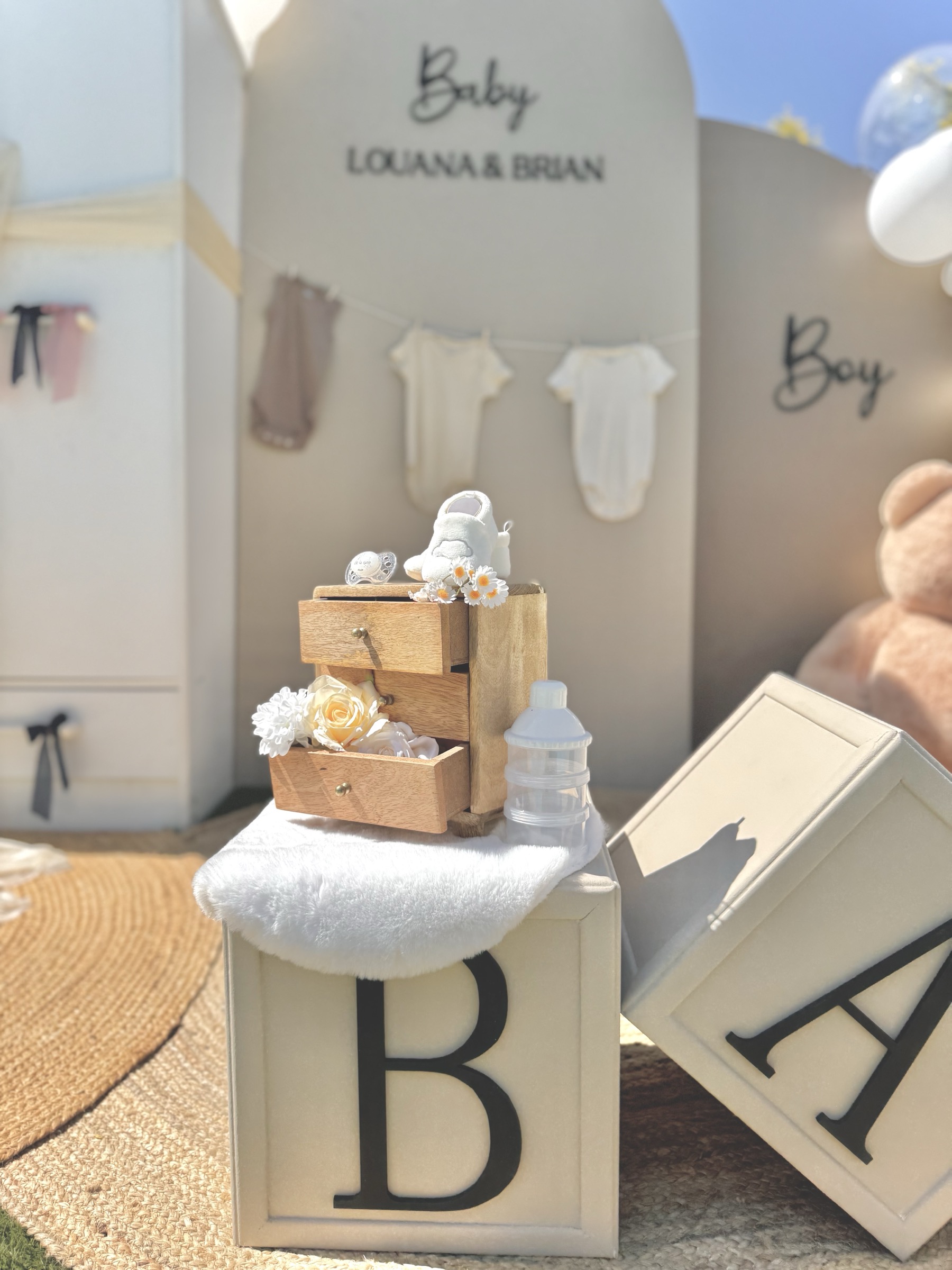 Détail décoration gender reveal — commode en bois, chaussures bébé et fleurs — Décore tes rêves