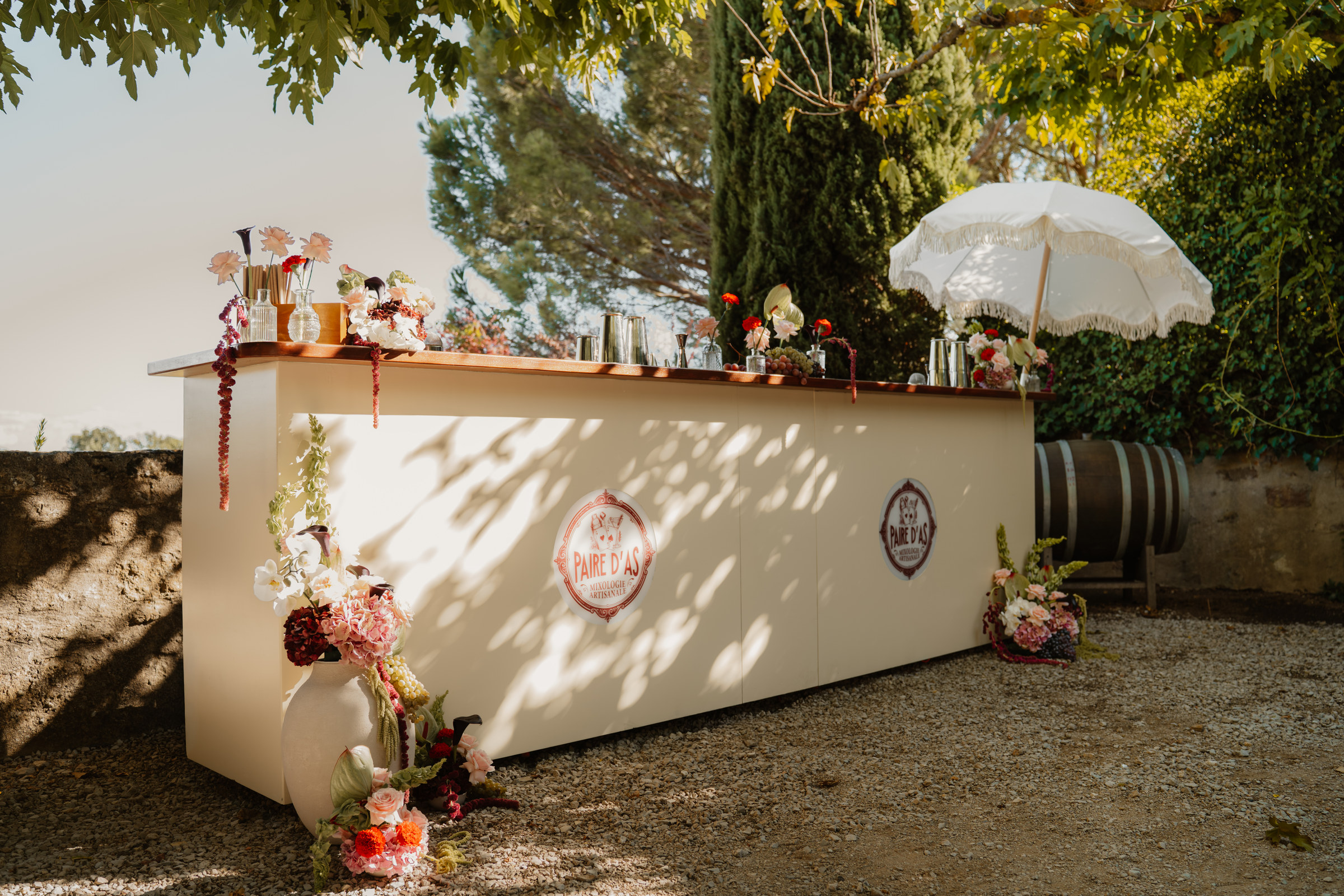 Bar de mariage en plein air habillé de fleurs, ombrelle et tonneau, Les Terres Saint-Hilaire