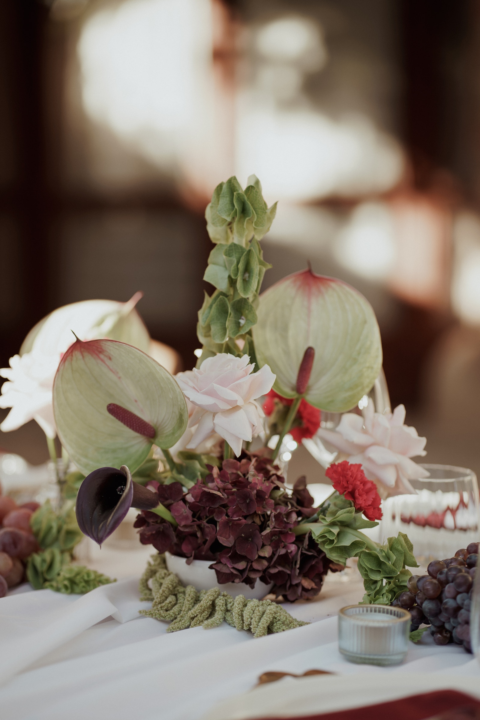 Centre de table de mariage avec anthuriums, callas bordeaux, roses poudrées et hortensias
