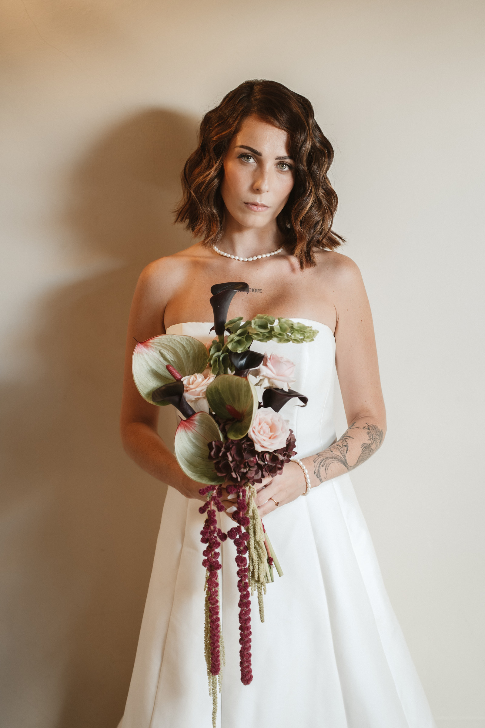 Mariée tenant son bouquet de callas et d'amarante, portrait élégant