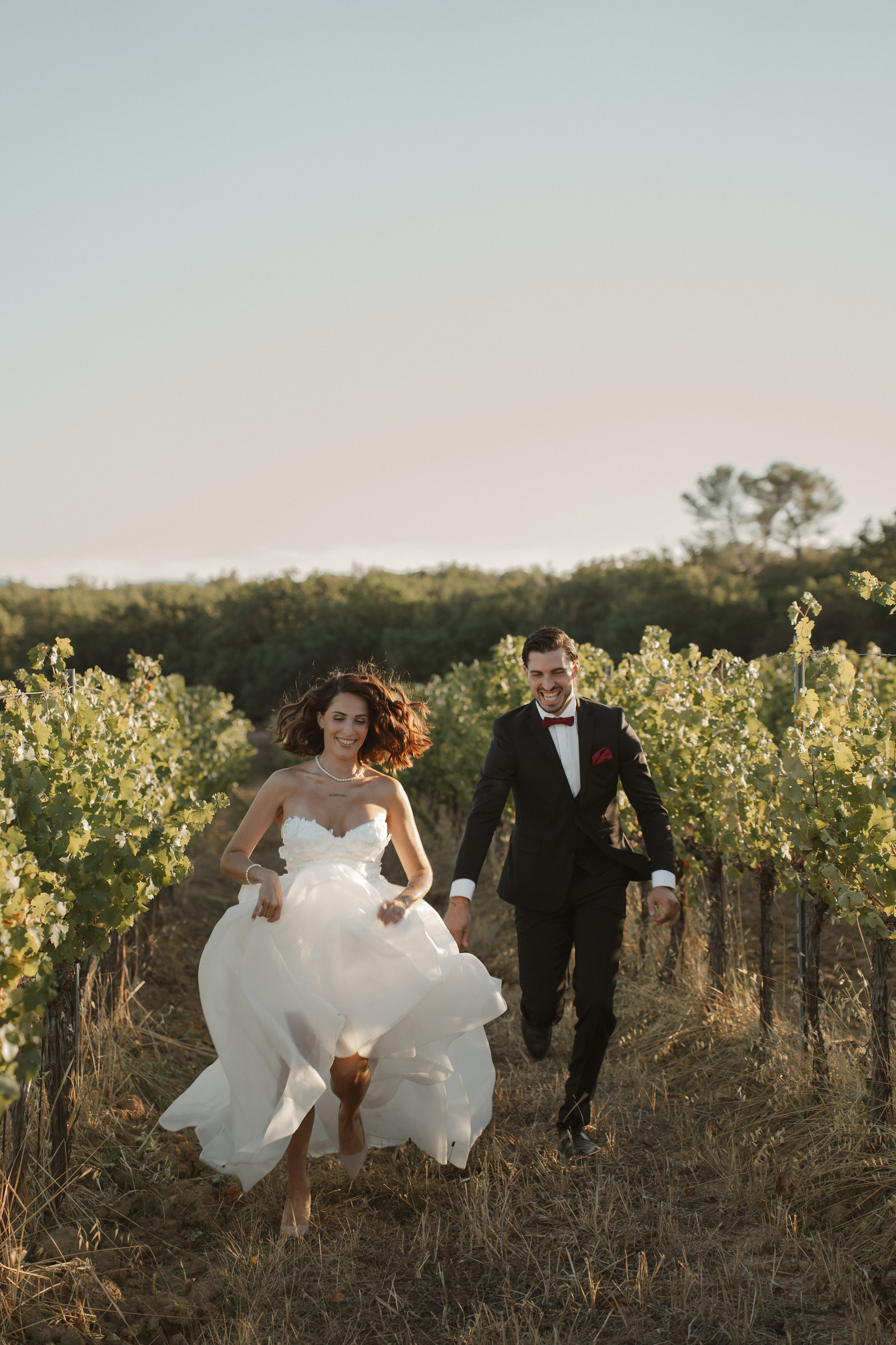 Mariés courant dans les vignes, robe au vent, shooting Vendanges Chic
