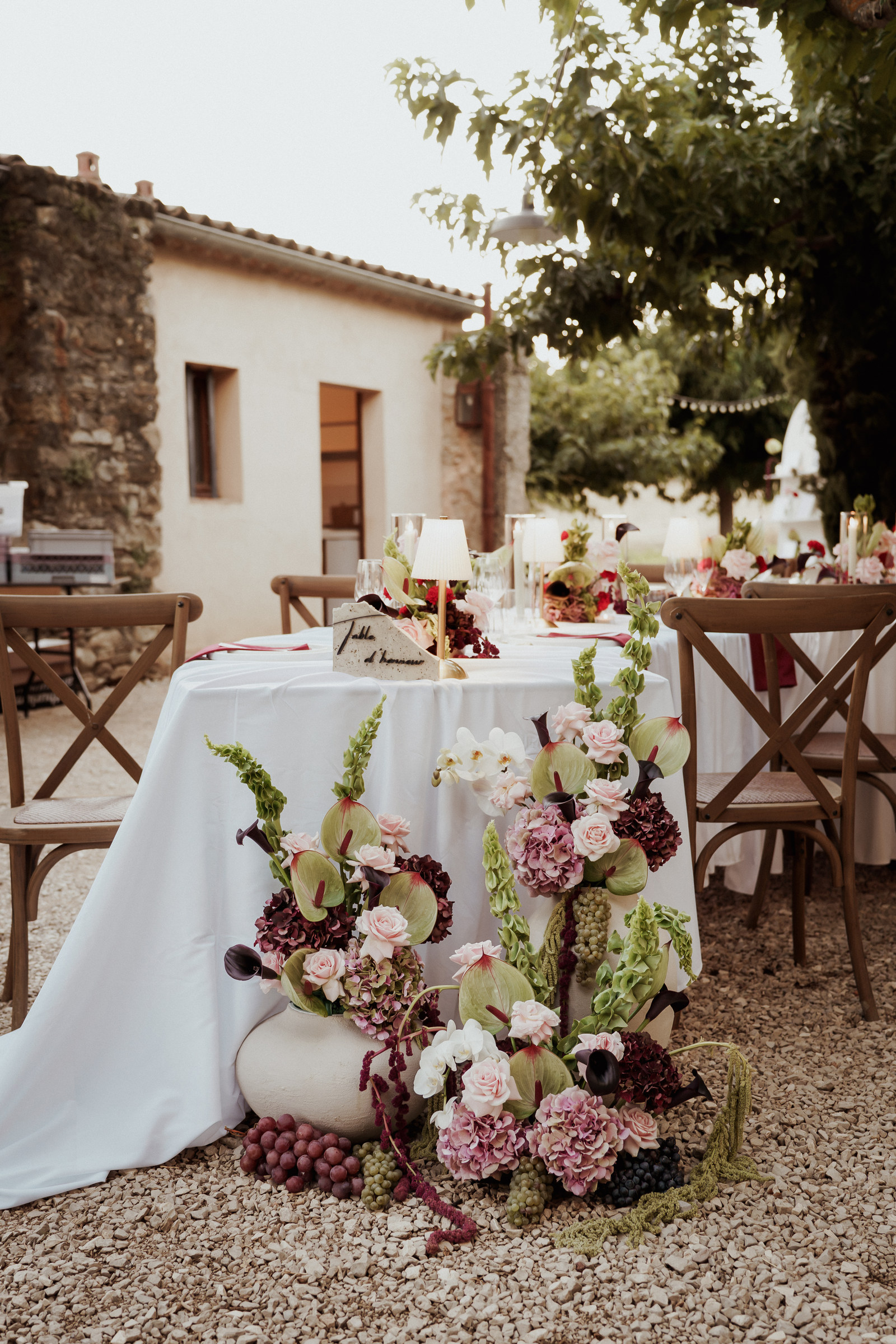 Table de réception fleurie sous les arbres, compositions au sol et raisin, mariage en Provence